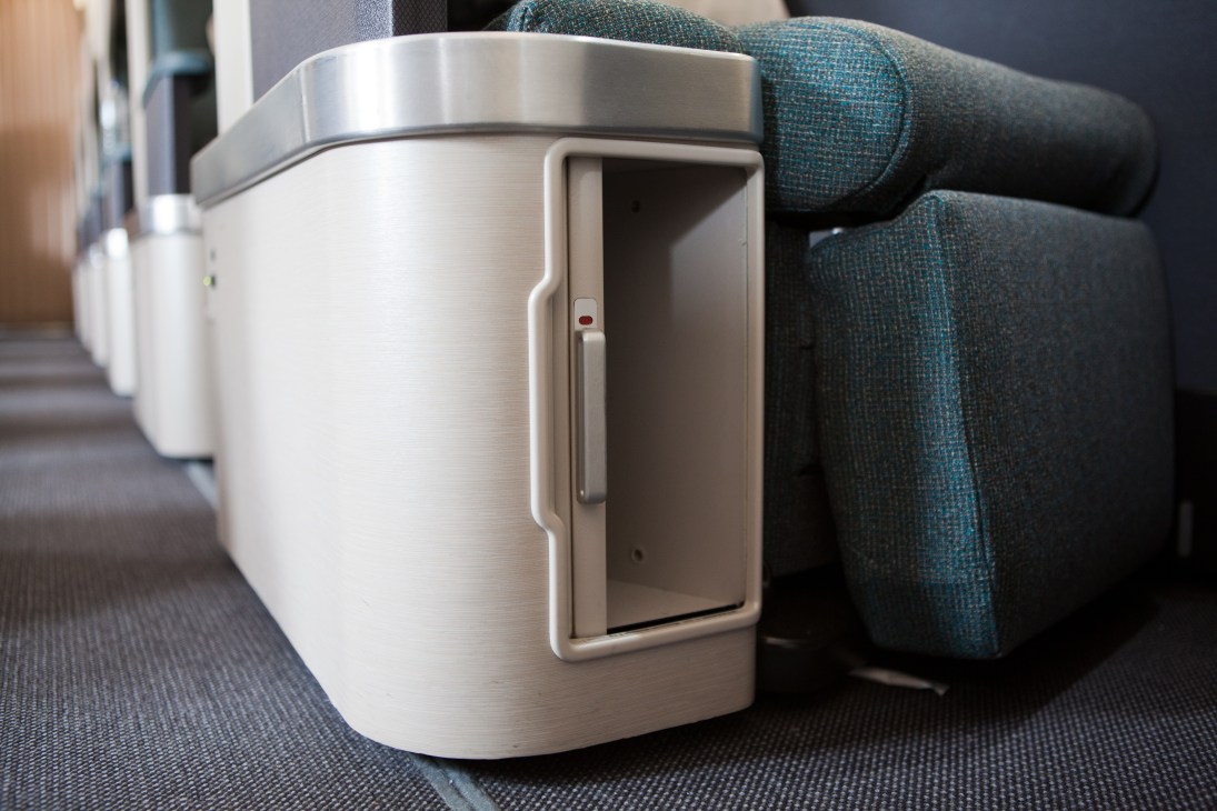 Cathay Pacific airline seat with white cylindrical armrest storage in business class cabin