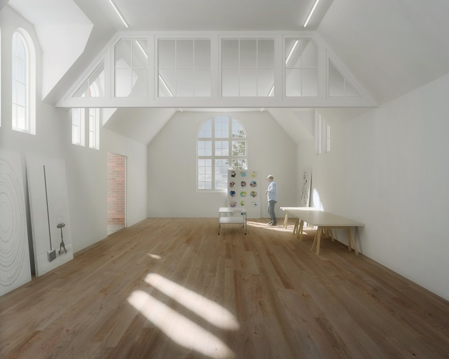 Bright studio space with wooden floors, white walls, large windows and natural light streaming across the room.