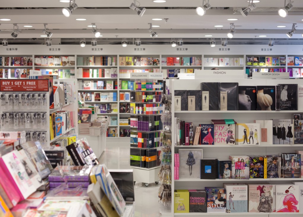 Page One airport newsstand displaying international magazines, books, and stationery with organized shelving and category signage.
