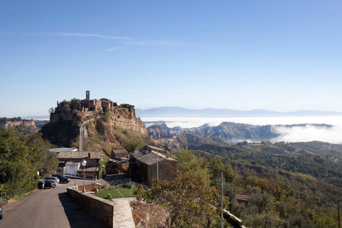 Medieval hilltop village of Civita di Bagnoregio perched on rocky outcrop surrounded by misty valleys and green landscape in central Italy.