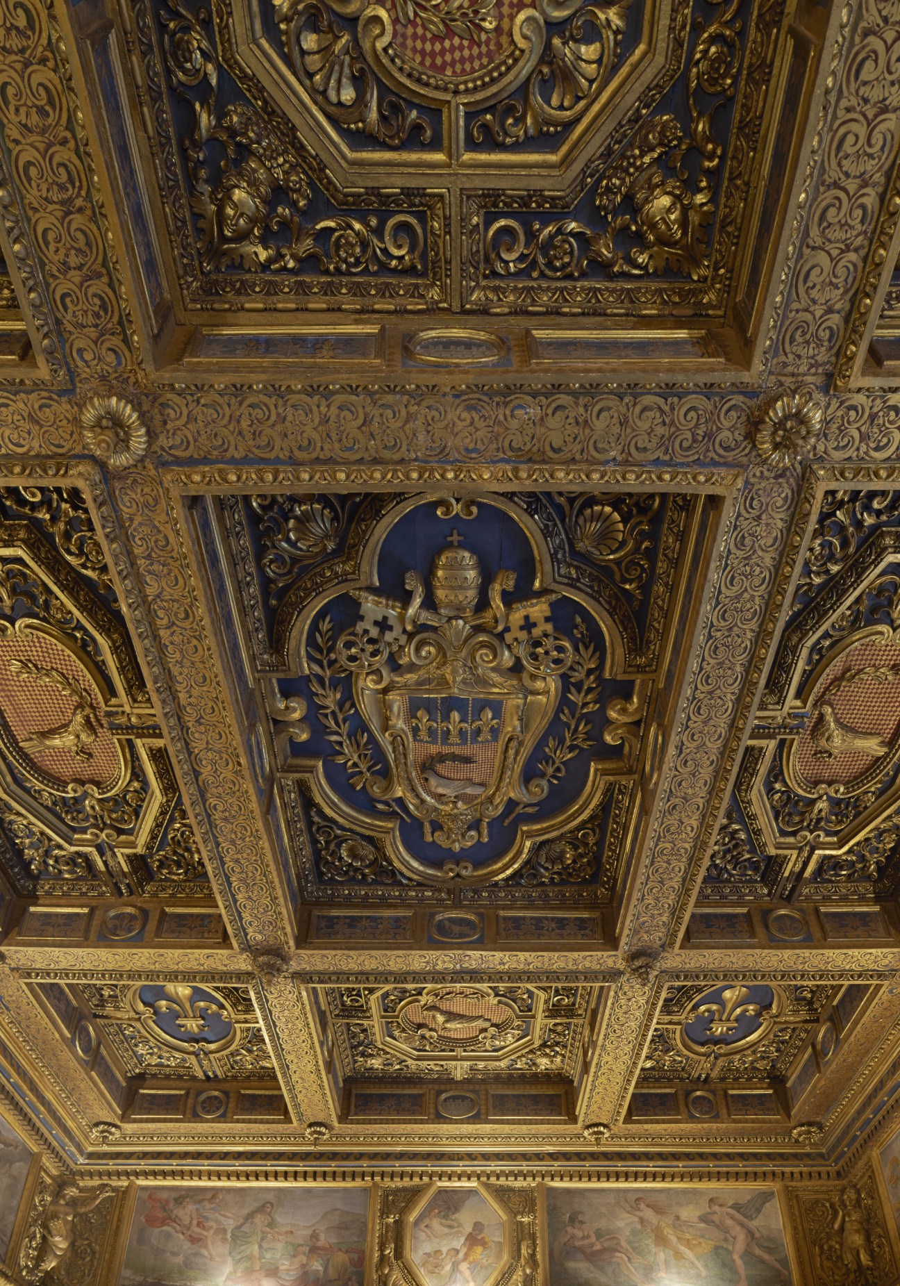 Ornate gold ceiling with blue coat of arms and elaborate Renaissance decorative patterns.
