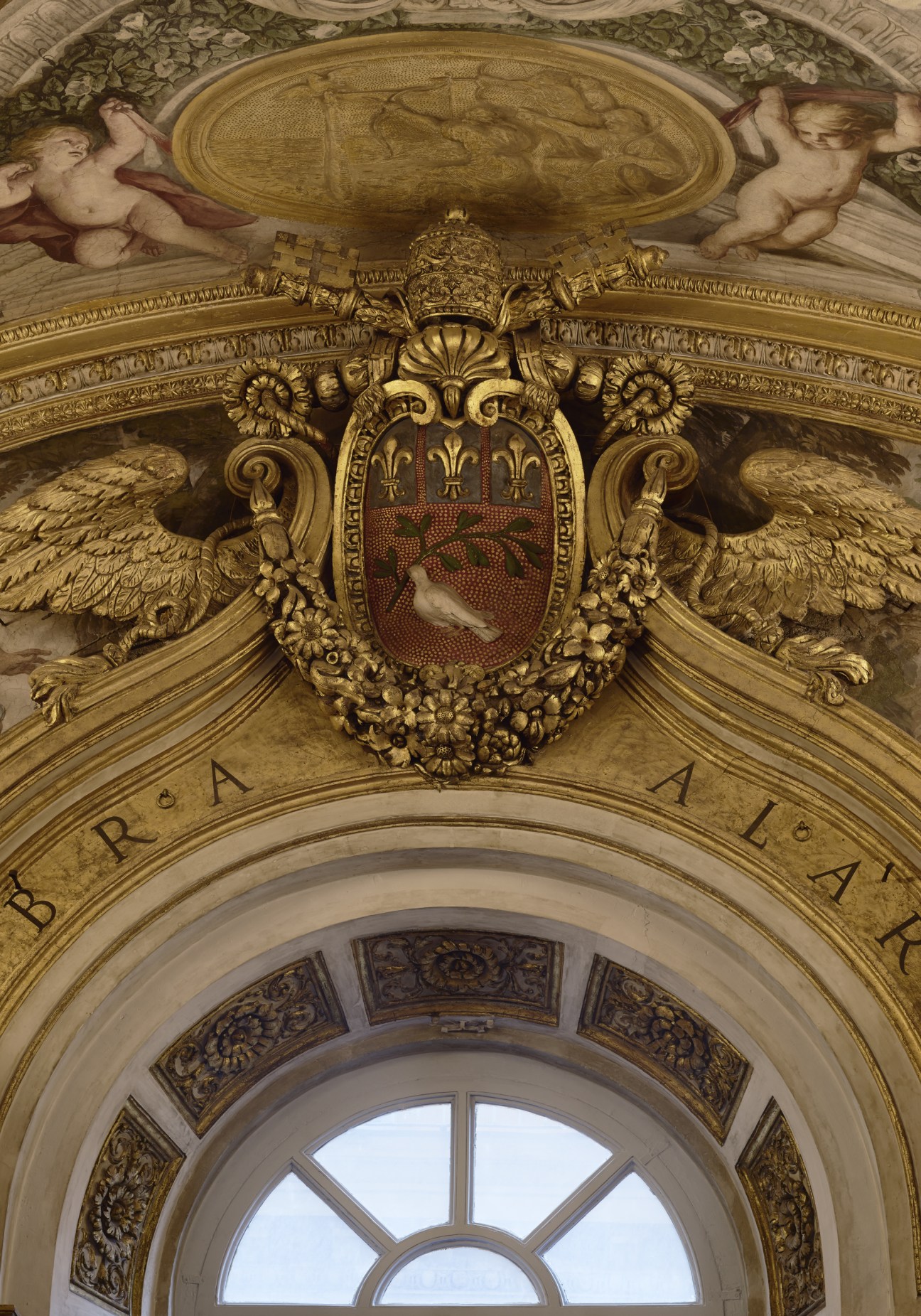 Ornate gilded ceiling detail featuring the Pamphilj family crest with winged eagles, dove and olive branch symbolism.