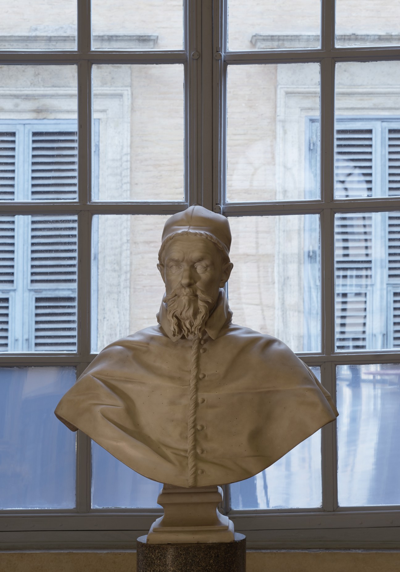 Bust sculpture of Pope Innocent X displayed against a large multi-paned window.