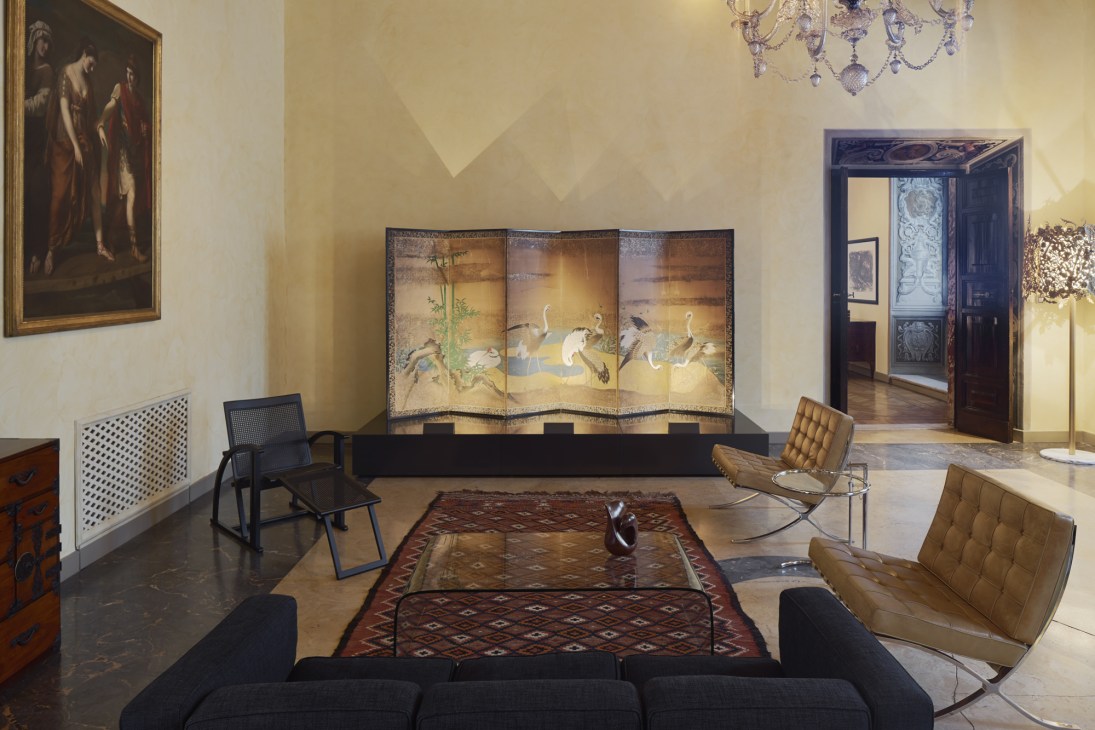 Interior room with modern furniture, Asian artwork panels, and classical paintings in an embassy residence.