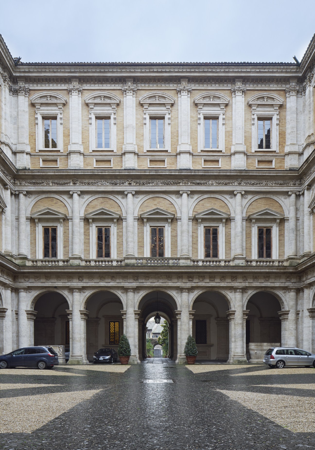 Courtyard of a grand Renaissance palazzo with symmetrical arched colonnades and classical stone architecture.