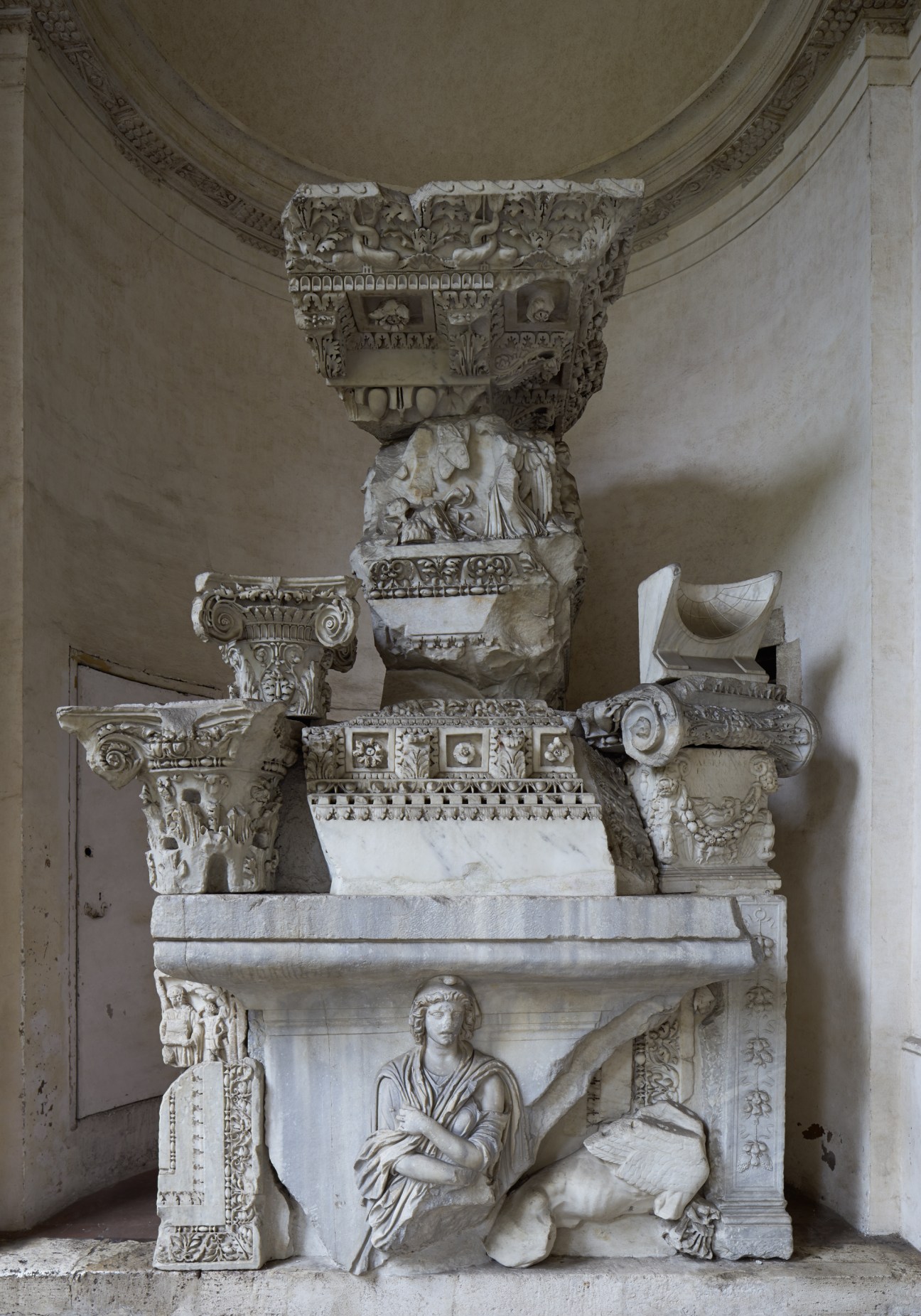 A 19th-century sculptural composition made from reassembled classical stone fragments and capitals, displayed against a curved ceiling.