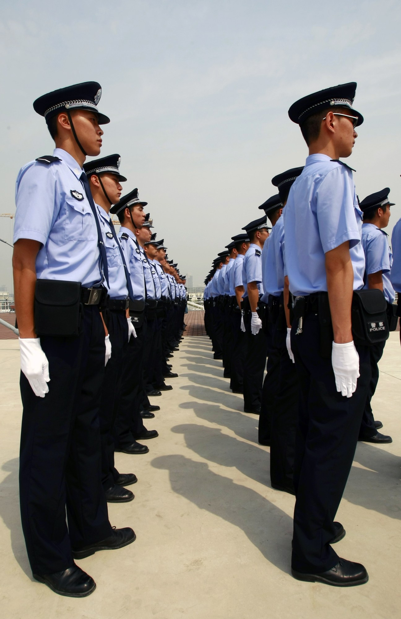 Chinese police officers in uniform standing in formation on a rooftop.