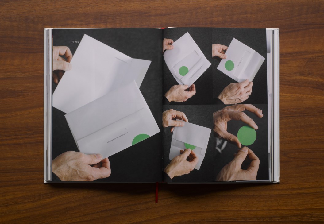 Open book displaying white cards with green circles held by hands against a dark background.