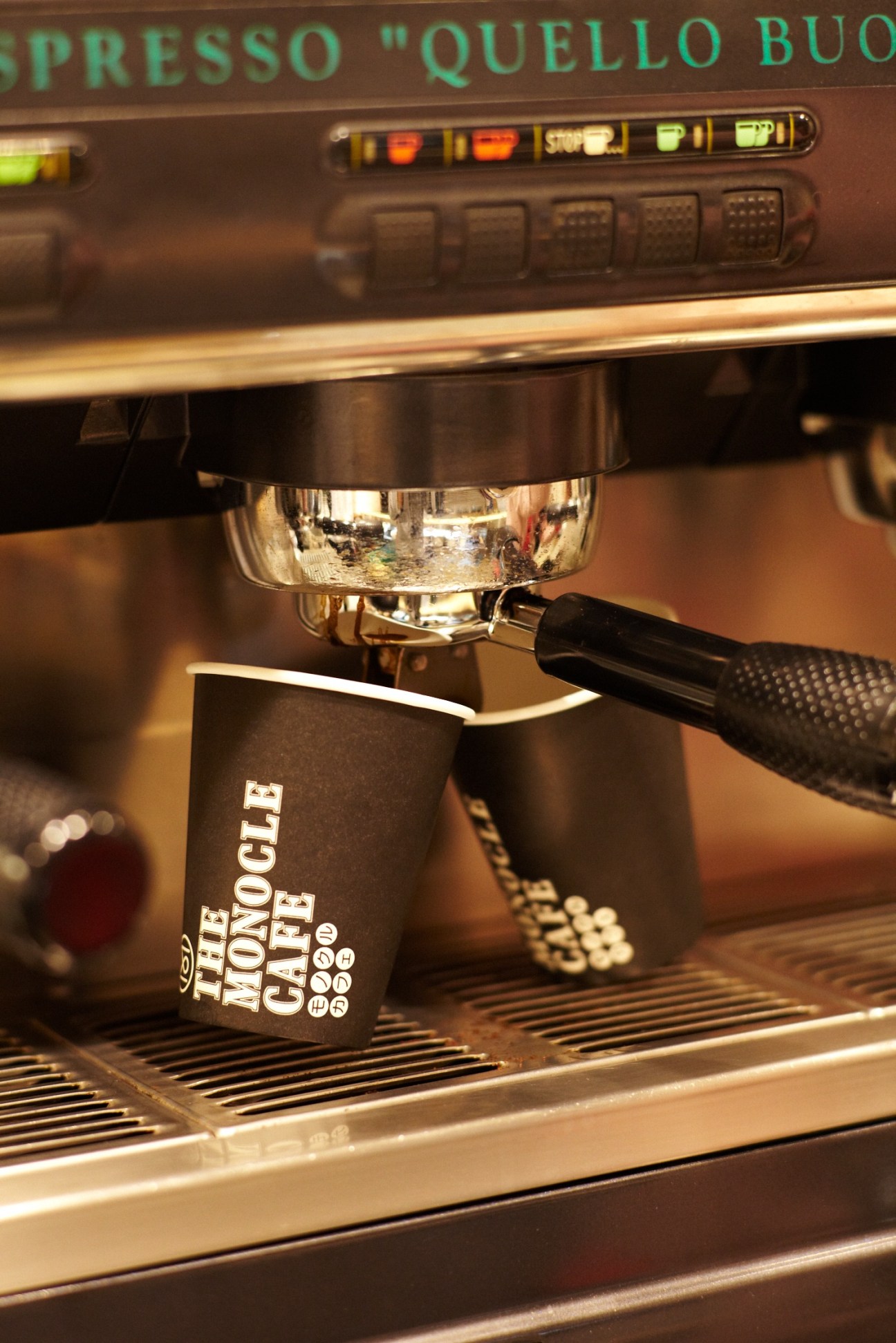 Espresso machine dispensing coffee into a black Monocle Café cup at Omotesando Koffee.