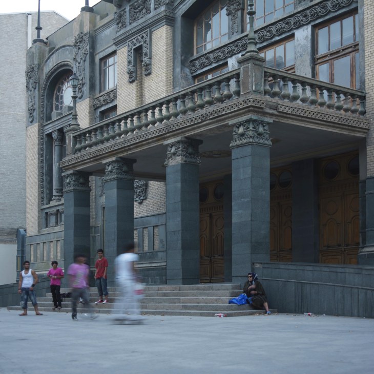 Skateboarders outside a grand ornate building with classical architecture and columns.
