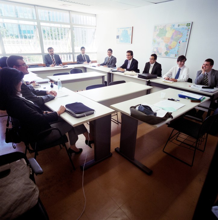 Young diplomats in business attire seated around tables during a Spanish language class.