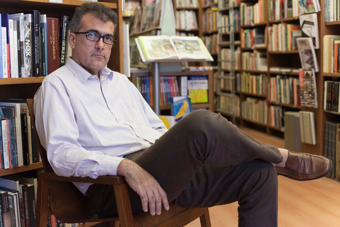 Giorgio Testa, manager of Archivolto bookshop in Milan, seated among shelves of architecture and design books.