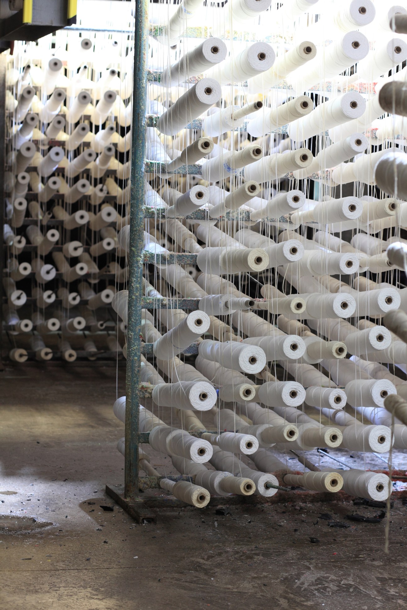 Spools of woven cotton wicks hanging on strings in the Cire Trudon factory.