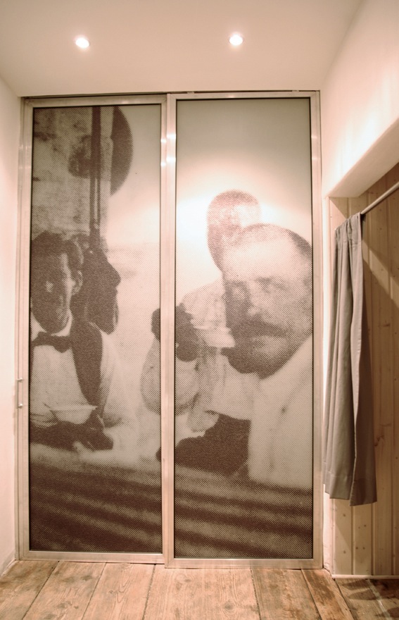 Two frosted glass doors with sepia-toned photographic prints of people, set in a wooden interior with recessed ceiling lights.