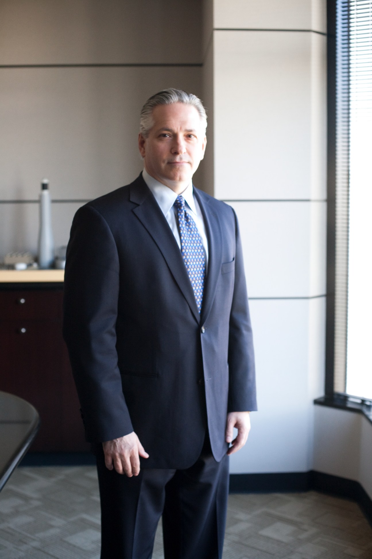 Kevin Smith, CEO of SolarReserve, stands in an office wearing a dark blue suit and patterned tie.