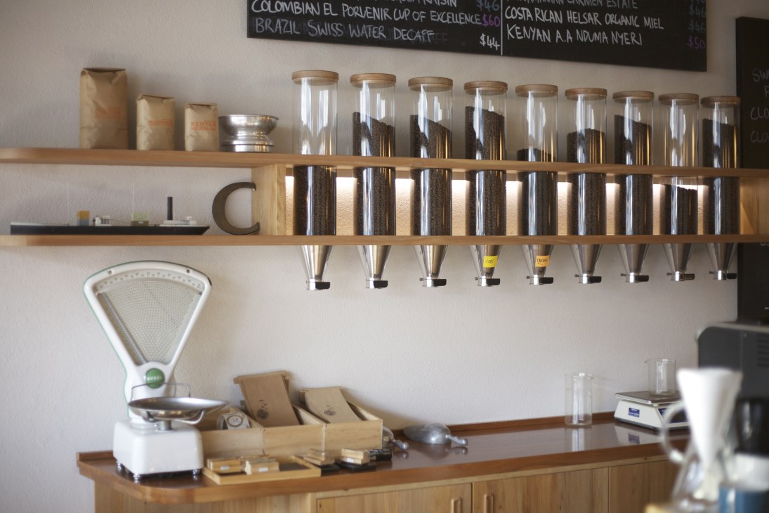 Coffee counter at Customs café in Wellington displaying glass jars of single-origin beans and brewing equipment.