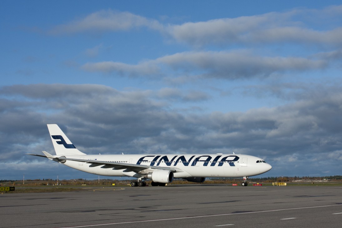 Finnair aircraft on airport tarmac with cloudy sky background.