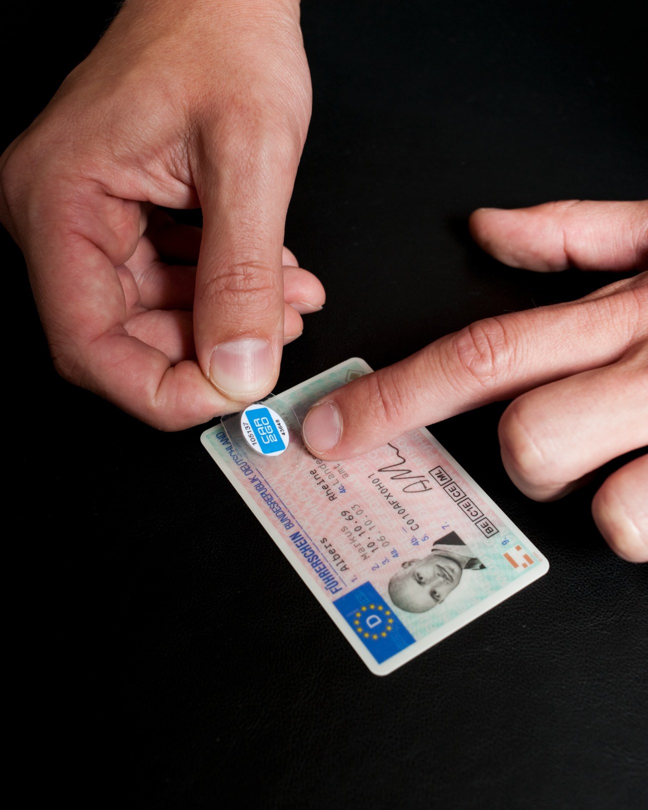 Hand holding a driving license with a car2go electronic tag attached to it