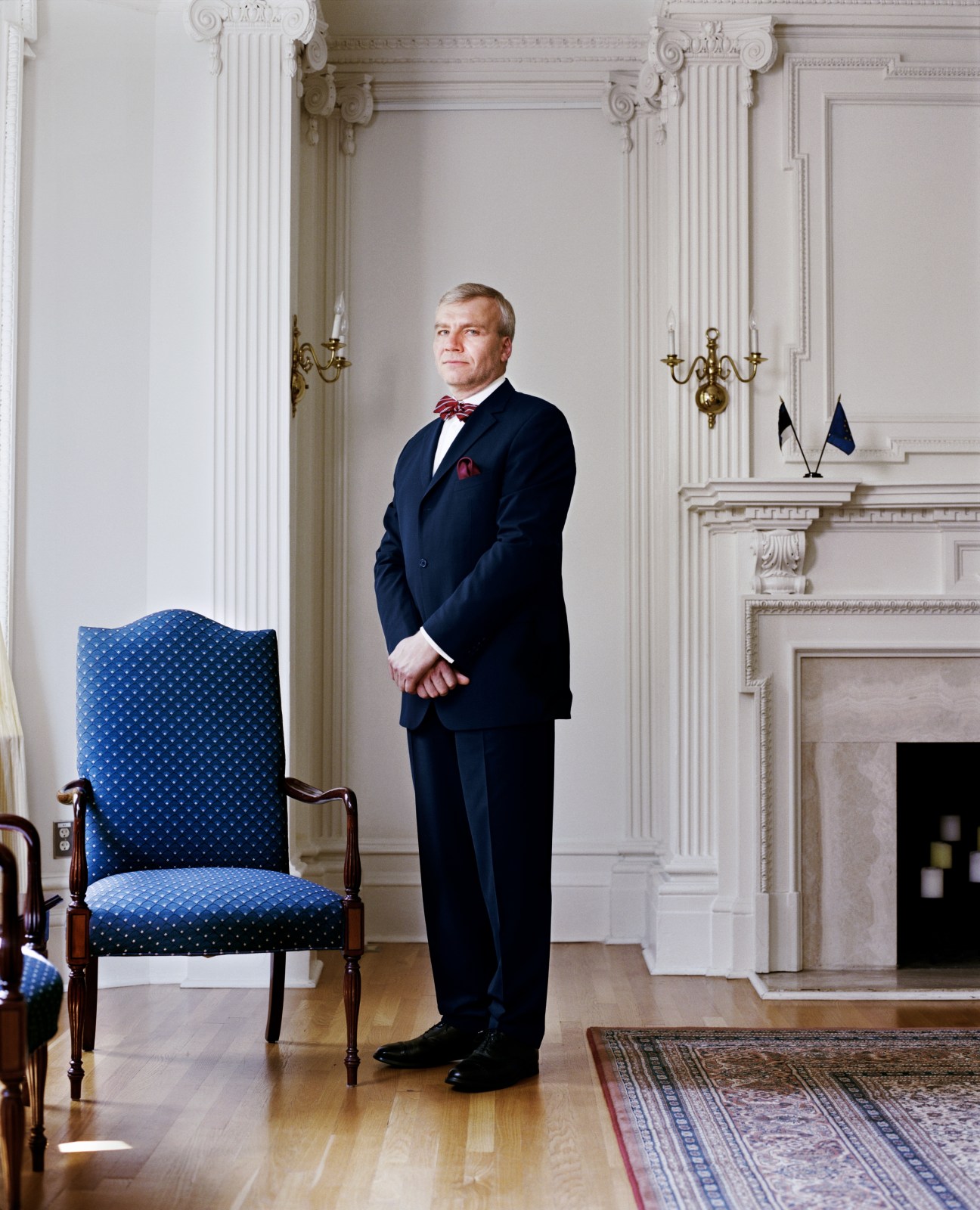 Väino Reinart, Ambassador of Estonia, standing in formal diplomatic setting with classical columns and fireplace.