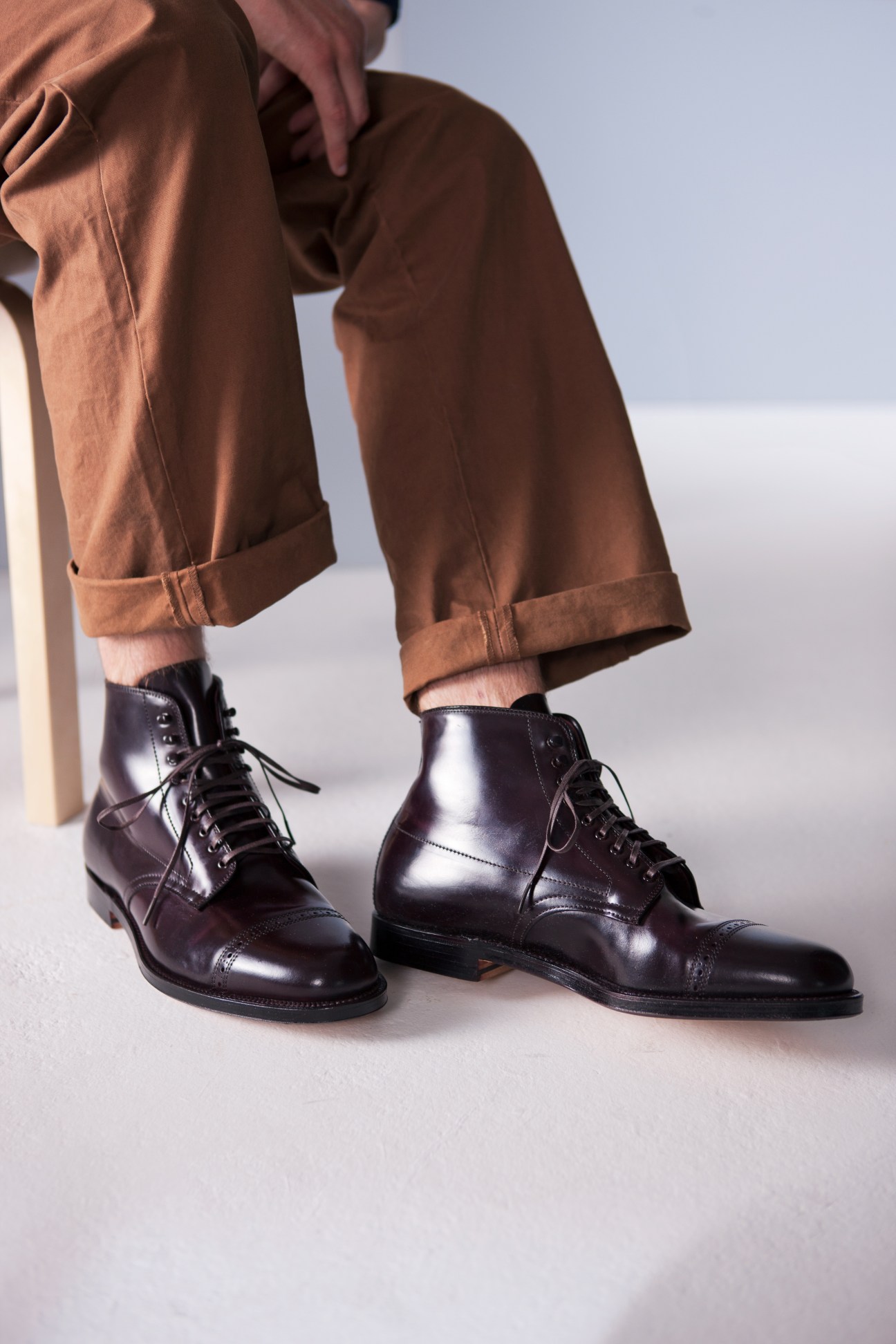 Person wearing tan chinos with rolled cuffs and black leather lace-up boots.