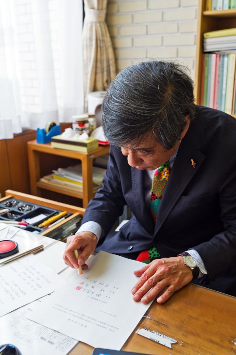 Mayor Ryozo Ichimura working at his desk in his office, reviewing documents.