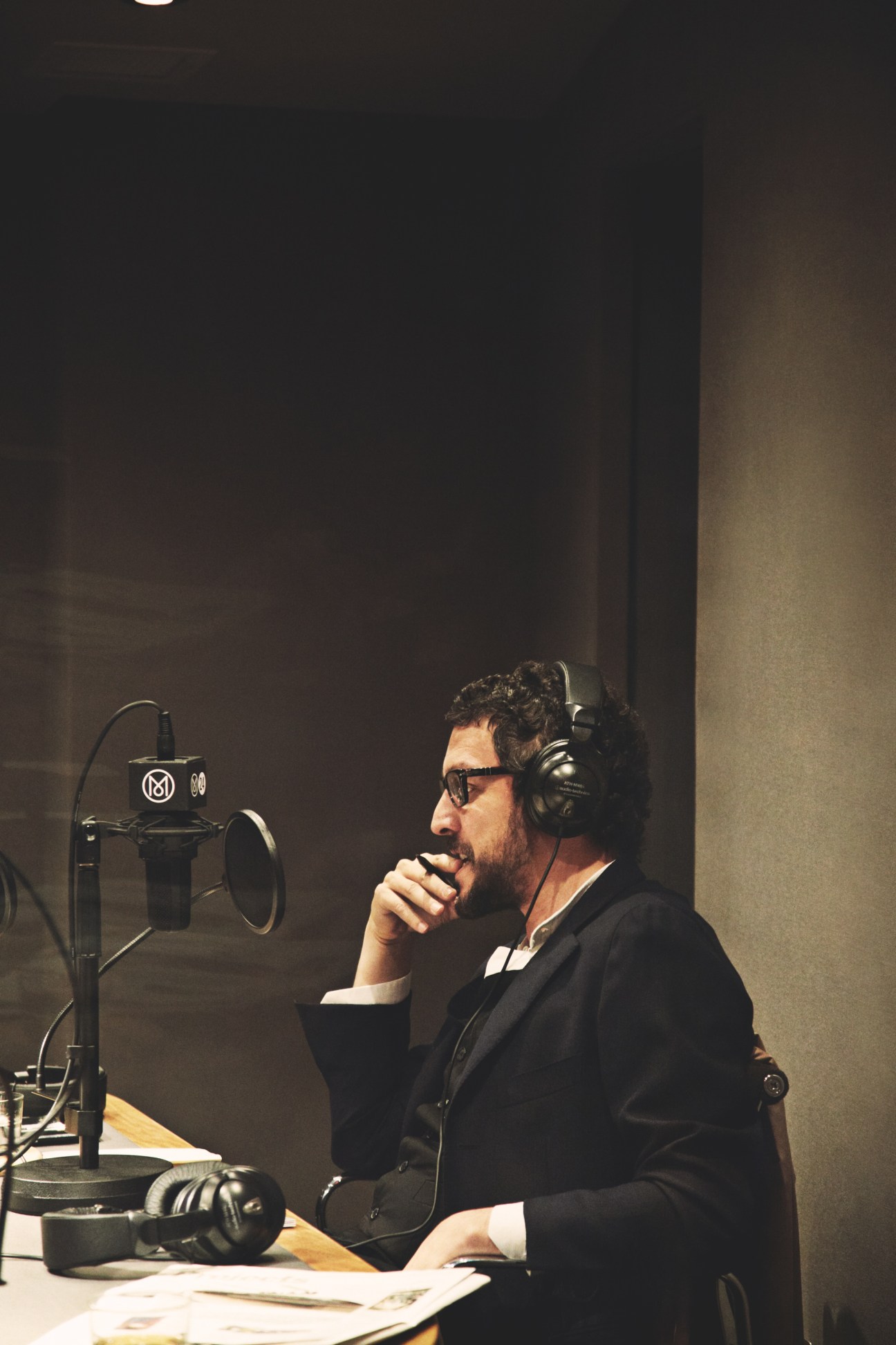 Guest Massimo Torrigiani, director of the Shanghai Contemporary Art Fair, speaking into a microphone in a studio wearing headphones and sunglasses.