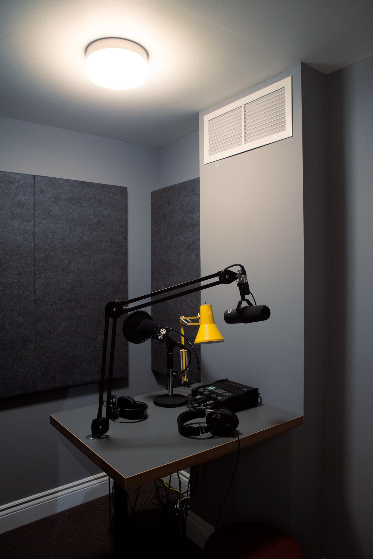 M24 radio studio with microphone, yellow lamp, headphones and soundproof panels.