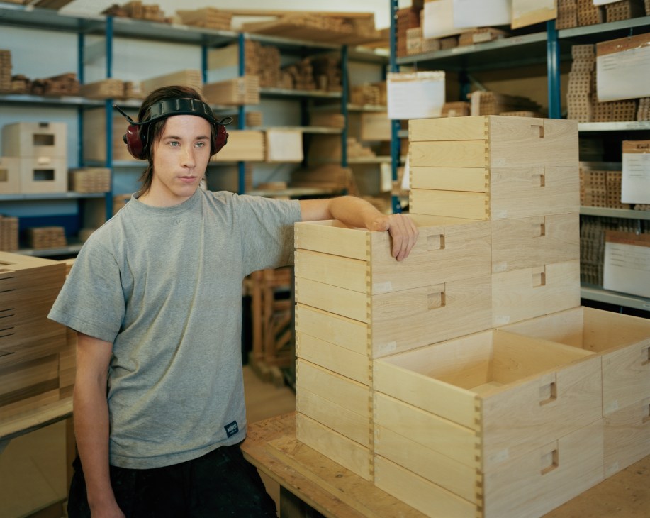 Jonas Andersson, carpenter at G.A.D, posing next to wooden furniture pieces in a workshop.