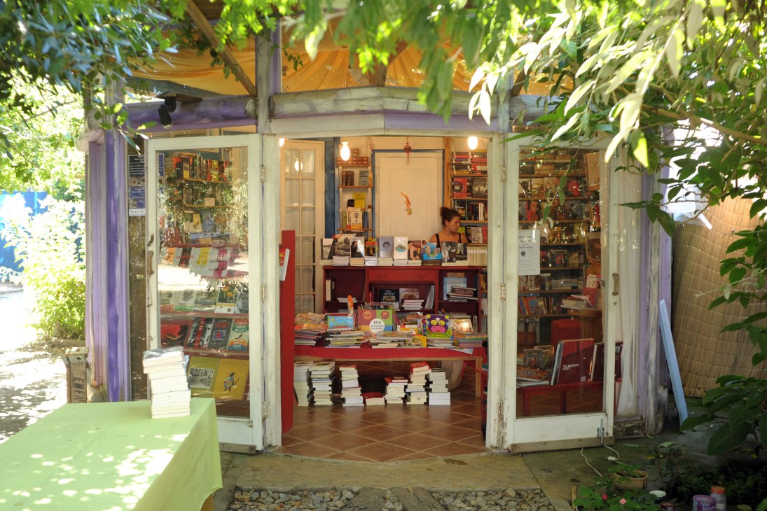 Moebius bookshop storefront with red shelving, books, and a shopkeeper visible through large windows.