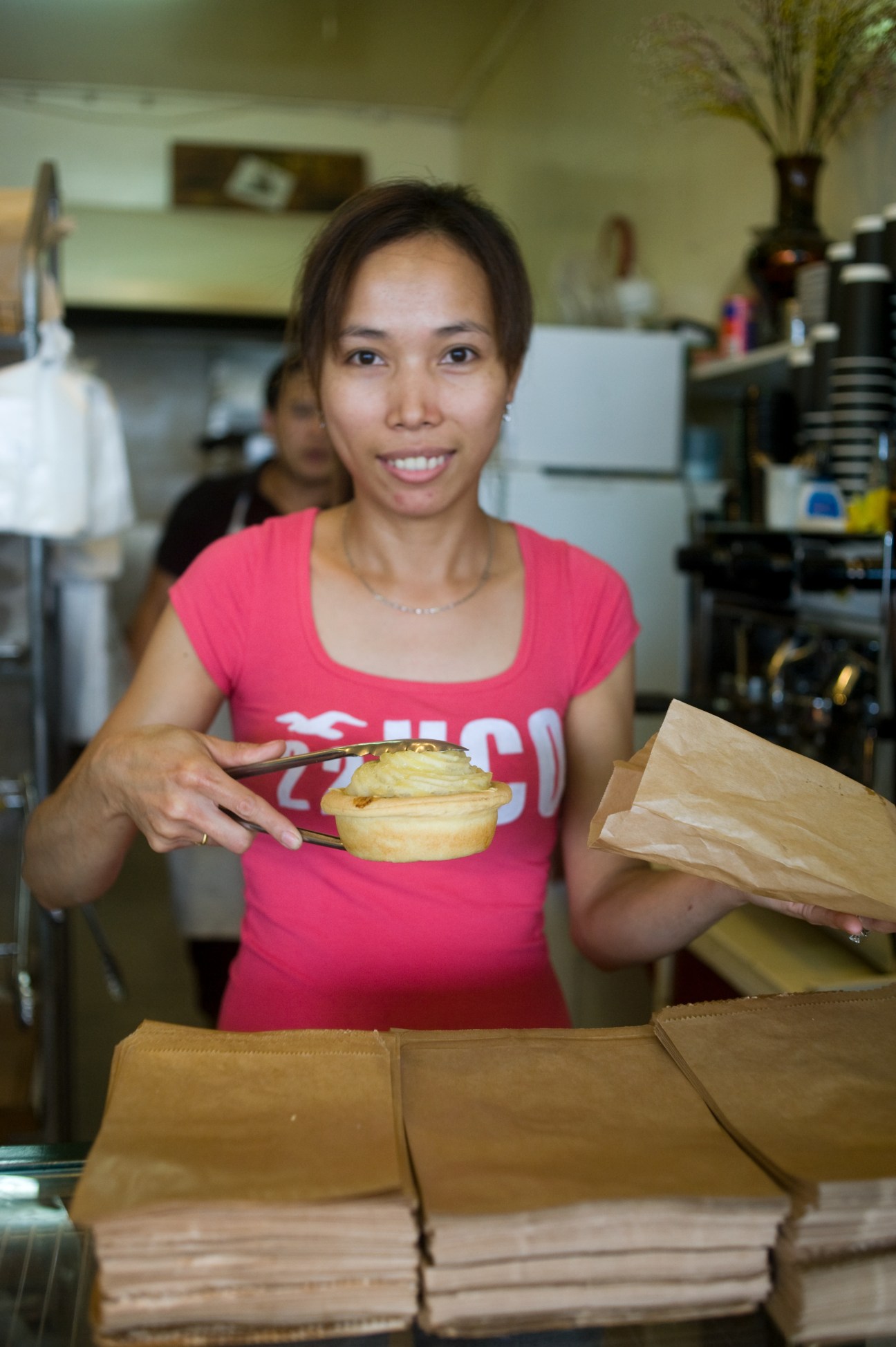 Staff member at Early Bird Bakery holding a pastry in the kitchen.