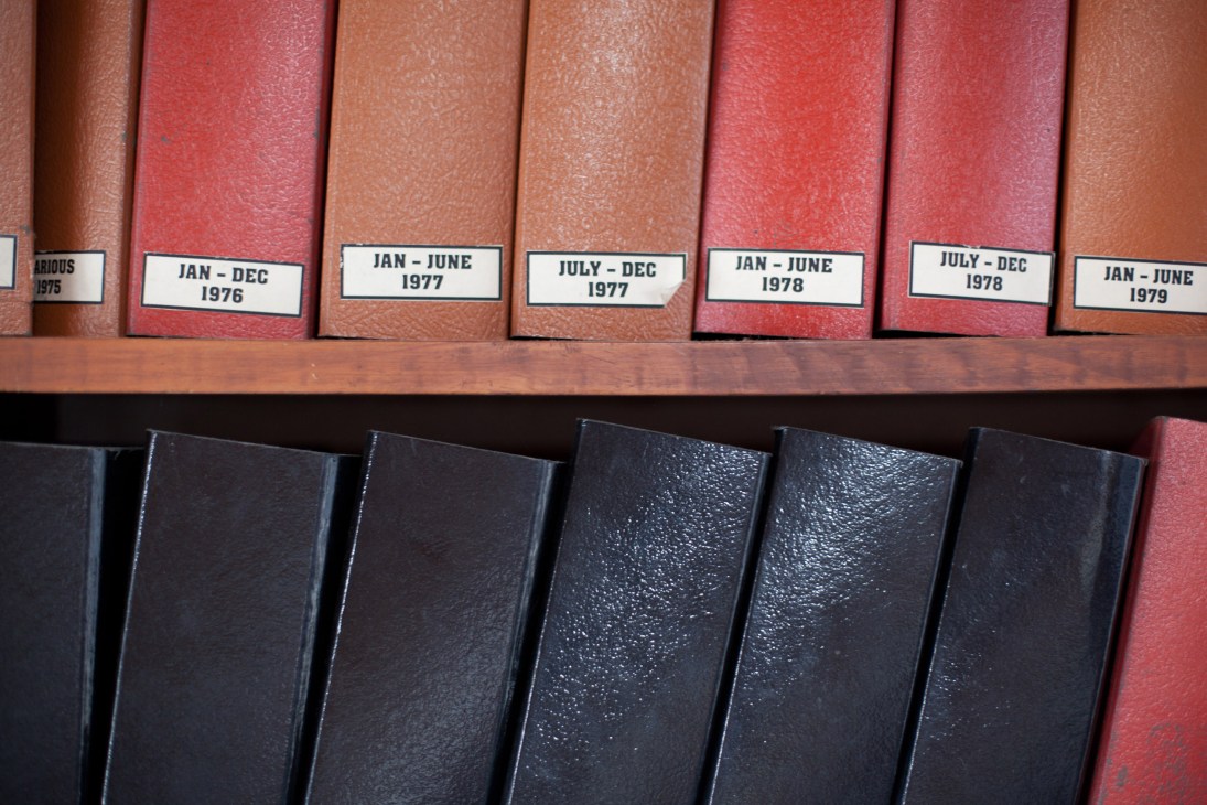 Archival bound volumes of Gulf News from 1975-1979 stored on wooden shelf.