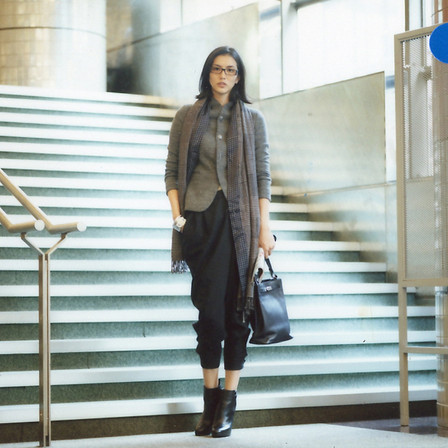 Woman in business attire descending stairs wearing Knott GV jacket, Des Pres cardigan, Ralph Lauren trousers, and Hermès accessories.