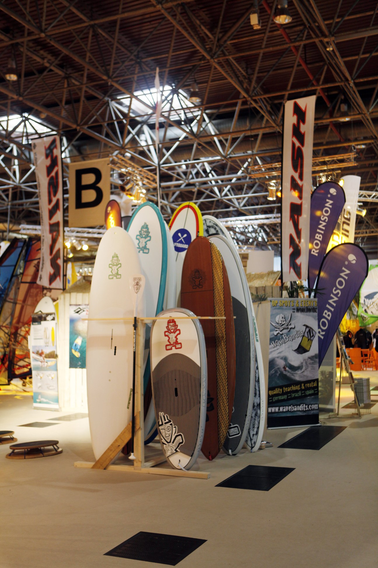 Paddle-boards displayed on wooden racks at Boot 2011 exhibition hall with industrial ceiling.