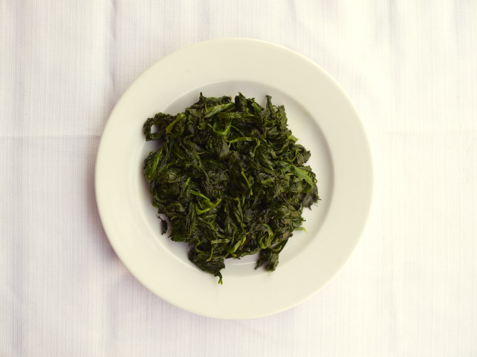 Sautéed spinach with olive oil, garlic and chilli pepper on a white plate.