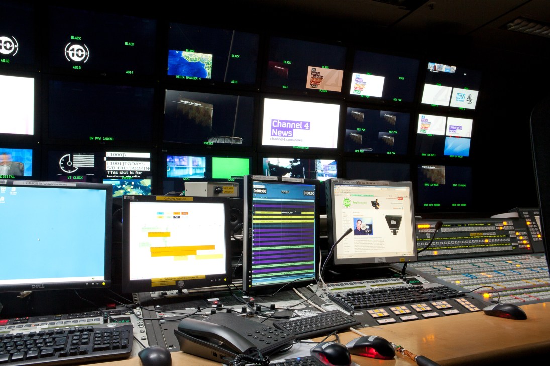 Channel 4 News control room with multiple monitors, keyboards, and broadcast equipment displaying video feeds and graphics.