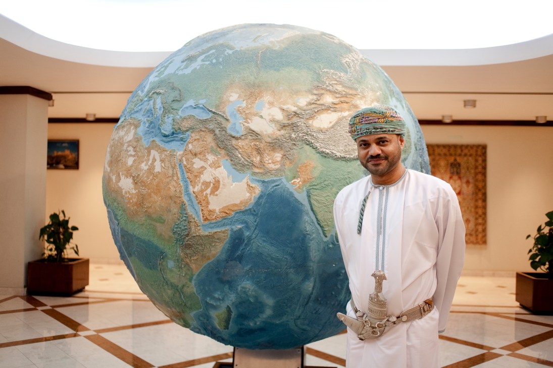 Badr Albusaidi stands beside a large spinning globe with no borders in the Ministry of Foreign Affairs lobby.