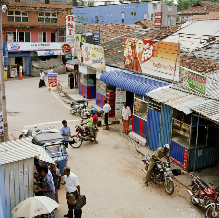 Street scene in central Hambantota showing small shops, motorbikes, and local residents in a rural Sri Lankan town
