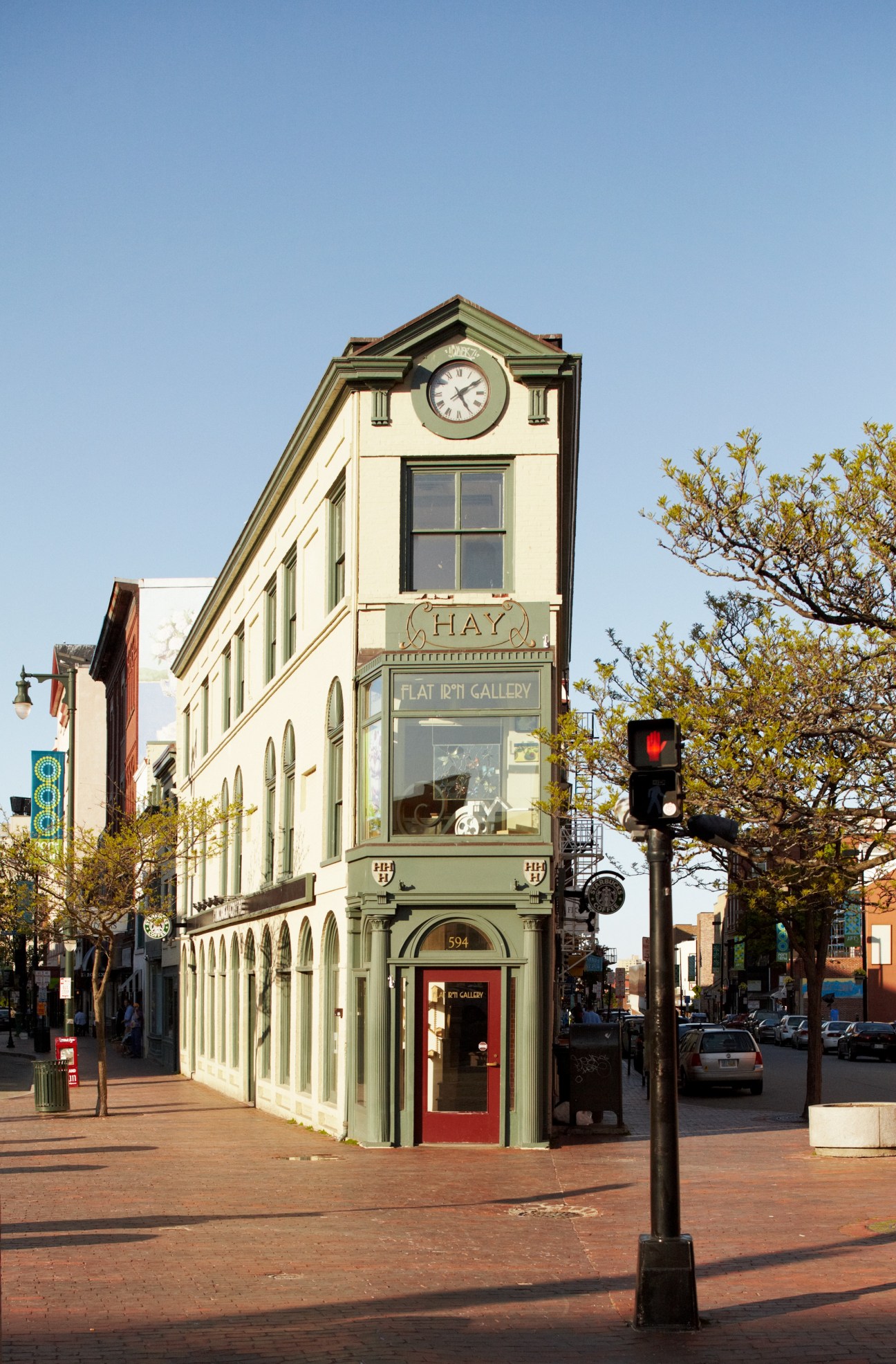Portland's Flatiron Building with clock tower and gallery storefront on brick street.