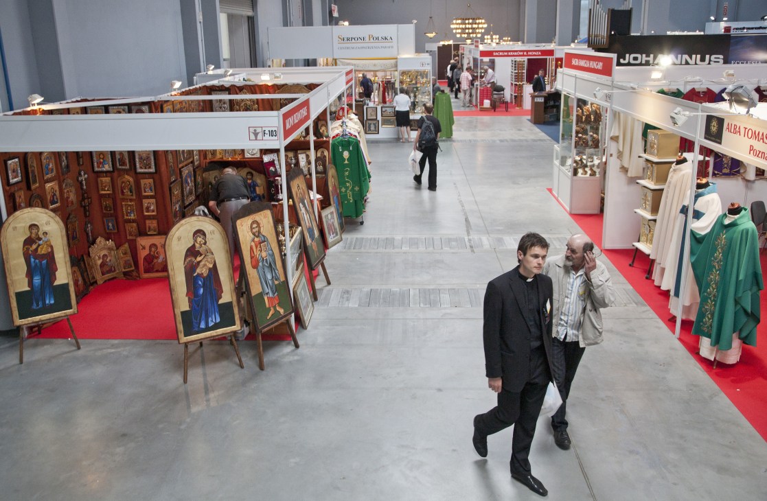 SacroExpo exhibition hall with religious vendors displaying icons, vestments, and ecclesiastical items along red-carpeted aisles.