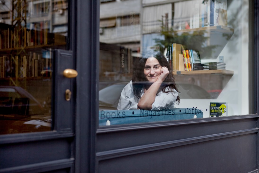 Rania Naufal, owner of Papercup bookshop, smiles while posing in the shop window display.
