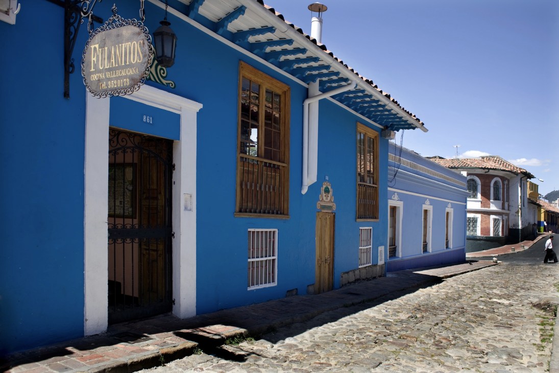 Bright blue colonial building with white trim and wooden doors on a cobblestone street in La Candelaria, Bogotá.