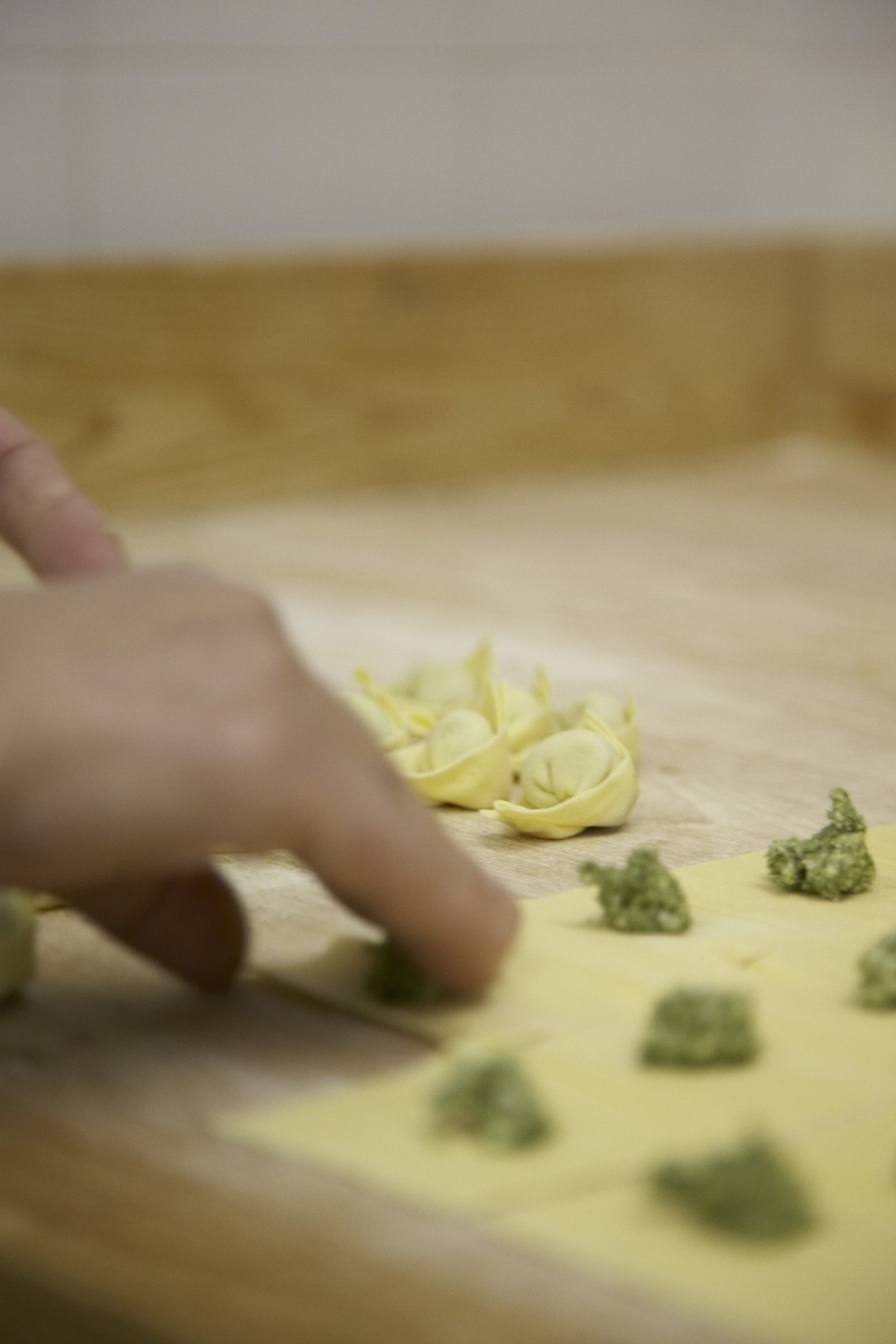 Hands shaping handmade pasta with green filling at Pasta Fresca Fiorella.