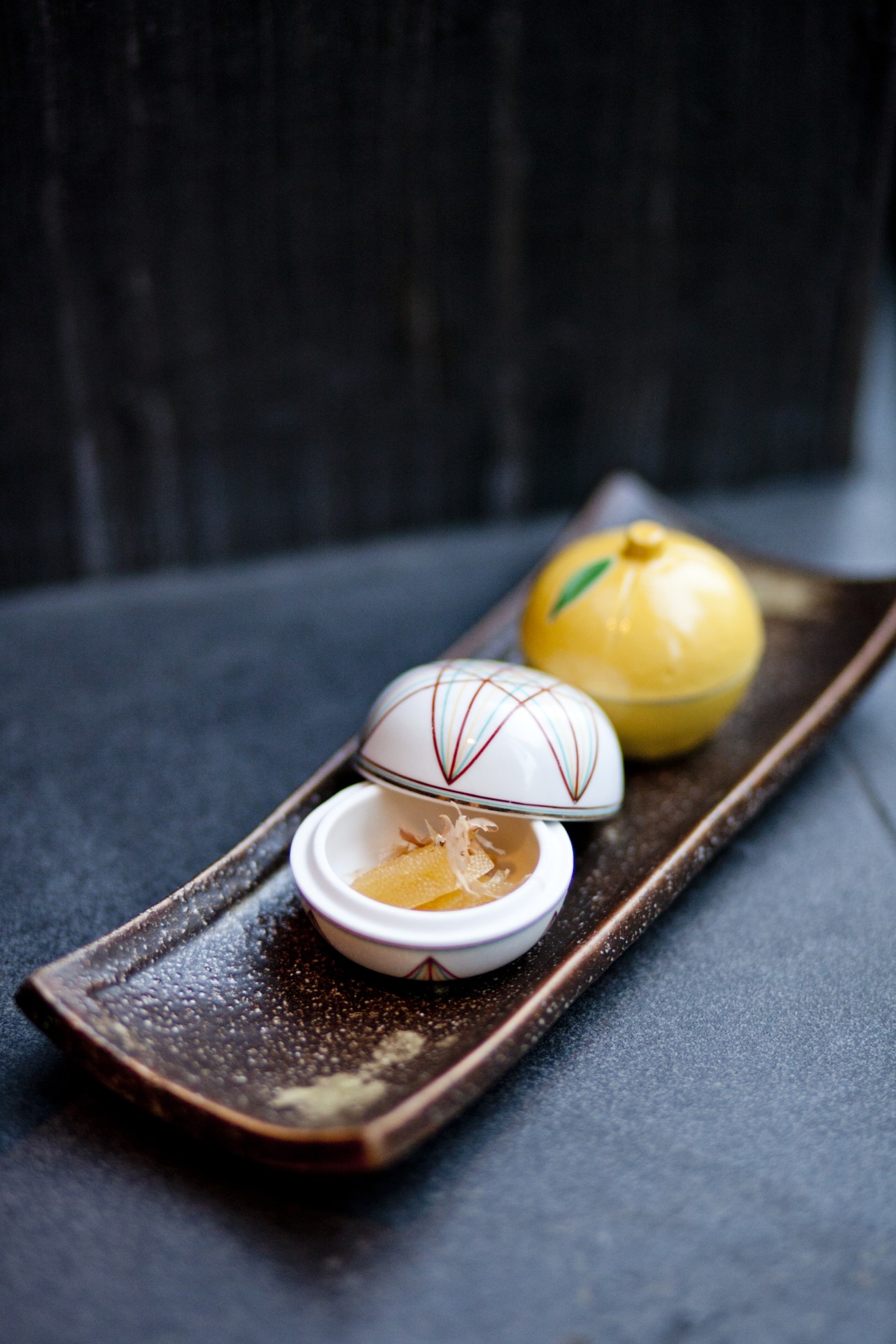 Delicate kaiseki cuisine dishes at Shiori restaurant in London, featuring decorative ceramic bowls with Japanese-style lids and garnishes on a wooden platter.