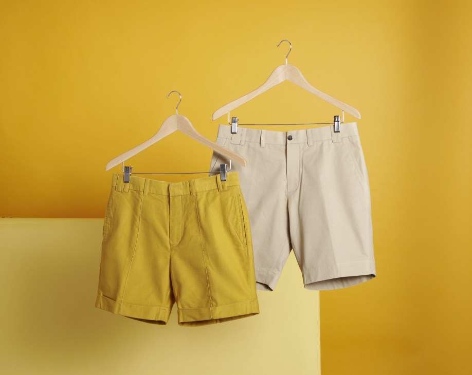 Two pairs of shorts on wooden hangers against a yellow background: saffron yellow and khaki-colored cotton shorts from JBB*.