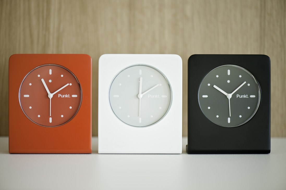 Punkt AC 01 alarm clocks displayed in red, white and black aluminum with minimalist dial design.