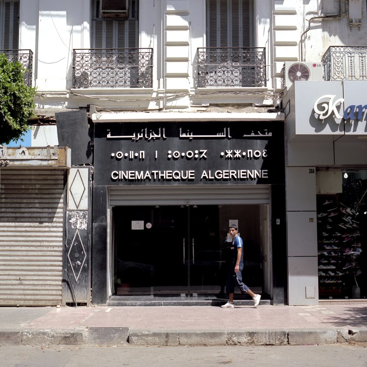 Cinematheque Algerienne storefront with dark facade and ornate balconies above