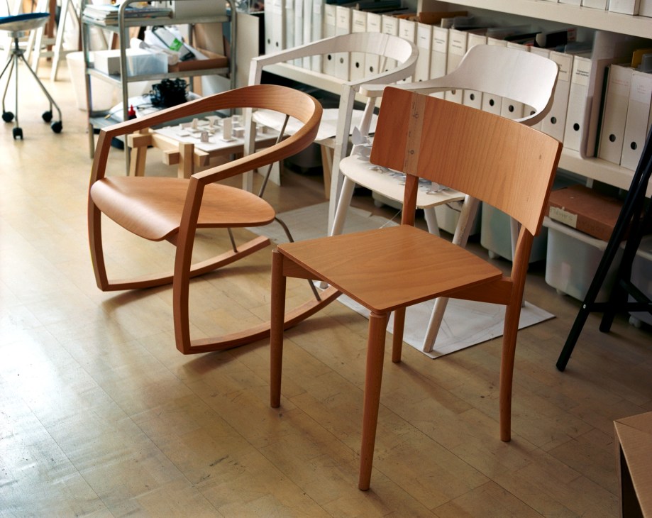 Wooden dining chairs with curved backs displayed in a design studio.