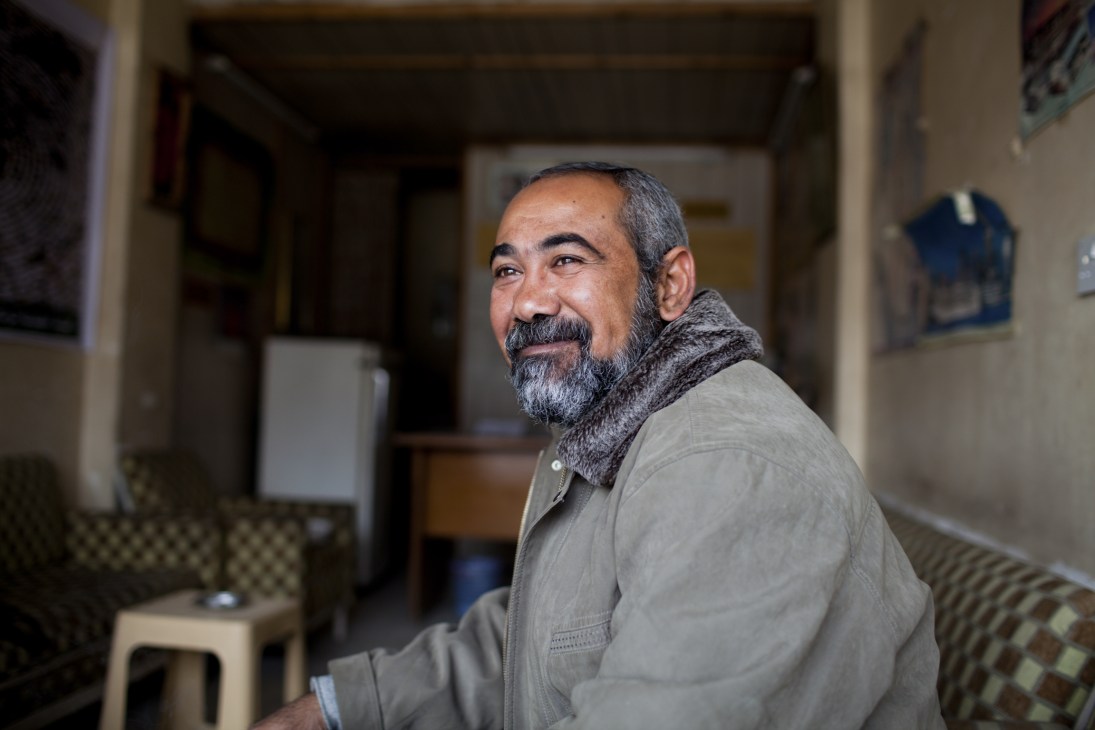 Estate agent Rafid Abud Jabar sits indoors wearing a grey jacket and patterned scarf.