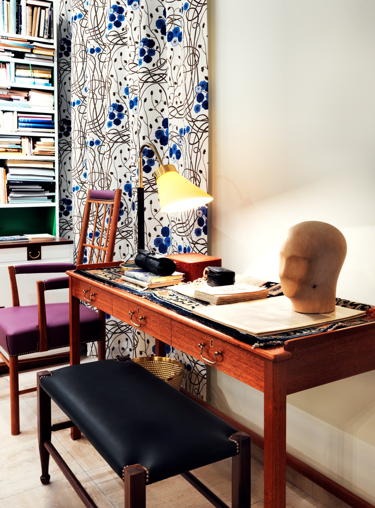 Desk display in Estrid Ericson's recreated office with wooden desk, chair, blue patterned wallpaper, and yellow lamp.