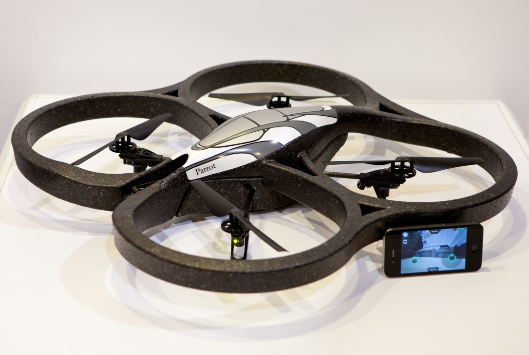 Parrot AR Drone quadcopter with black arms and white body displayed with smartphone controller showing video feed.